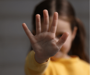 child with hand blocking face