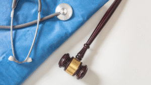 A stethoscope on blue fabric next to a judge’s gavel on a white surface.