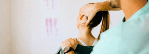 A physiotherapist adjusts a woman's neck and upper back during a therapy session.