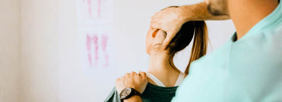 A physiotherapist adjusts a woman's neck and upper back during a therapy session.