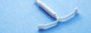 A white intrauterine device (IUD) is shown on a blue background.