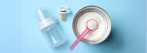 A baby bottle, a pacifier, and an open can of powdered infant formula with a scoop are arranged on a blue background.