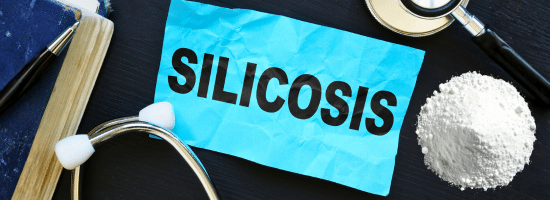 A blue paper with the word "Silicosis," near a stethoscope, a mound of white powder, a notebook, and a magnifying glass on a dark surface.